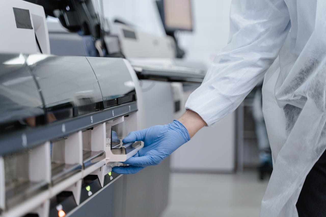 Lab technician in a white coat using equipment with precision in a sterile environment.