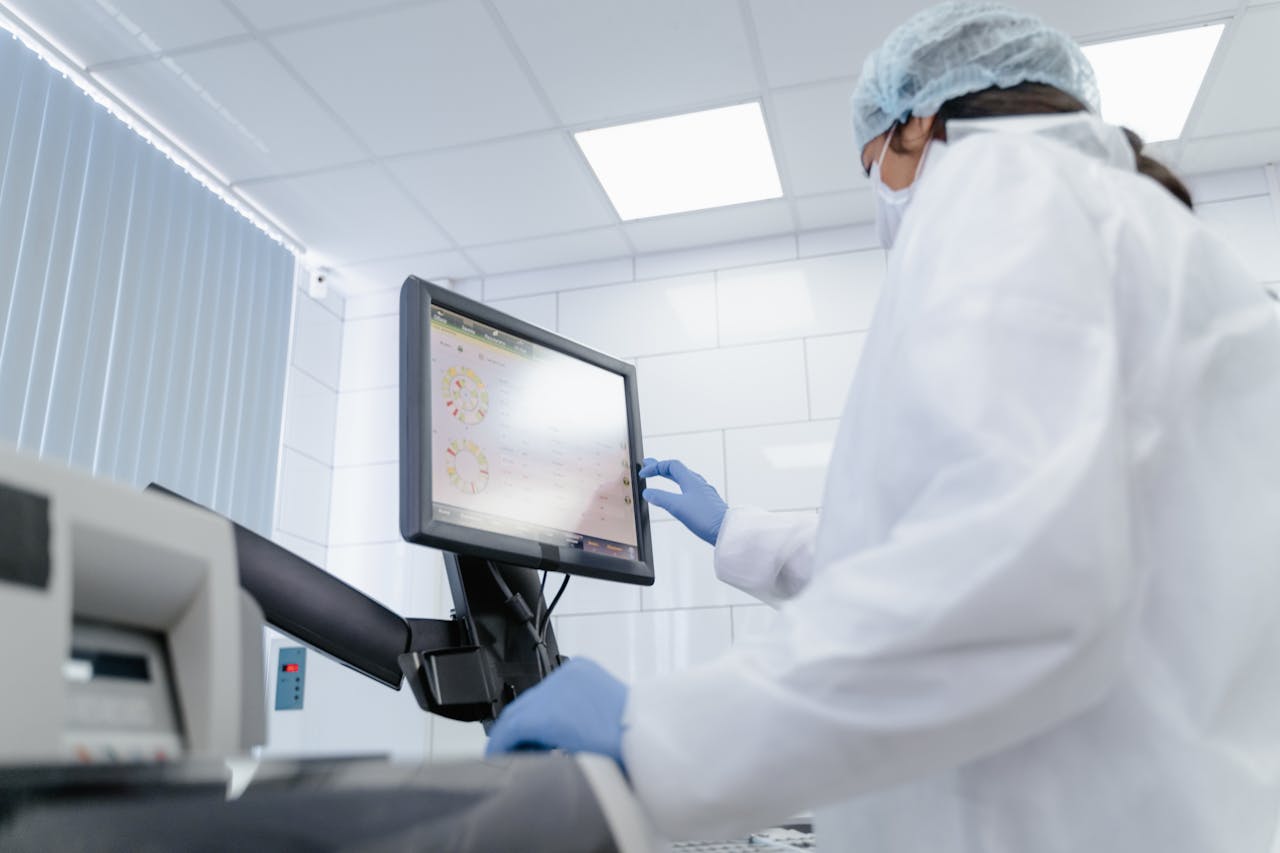 Woman in lab coat using touchscreen monitor in a modern laboratory setting.